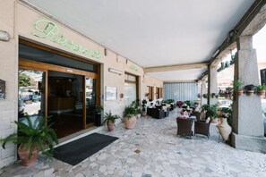 Um restaurante com um pátio ladrilhado, plantas em vasos e mesas ao ar livre.