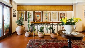 A lobby with a large wooden panel, a patterned rug, and several potted plants.