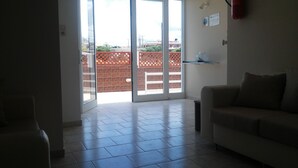 A living room with a sliding glass door leading to a patio area. - Dimitra Apartments (Hersonissos)