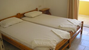 A twin room with two single beds, a small bedside table, and a plain wall. - Dimitra Apartments (Hersonissos)