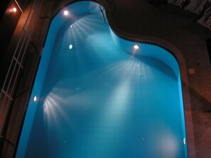 A swimming pool with a curved edge and multiple lights around its perimeter. - Dimitra Apartments (Hersonissos)