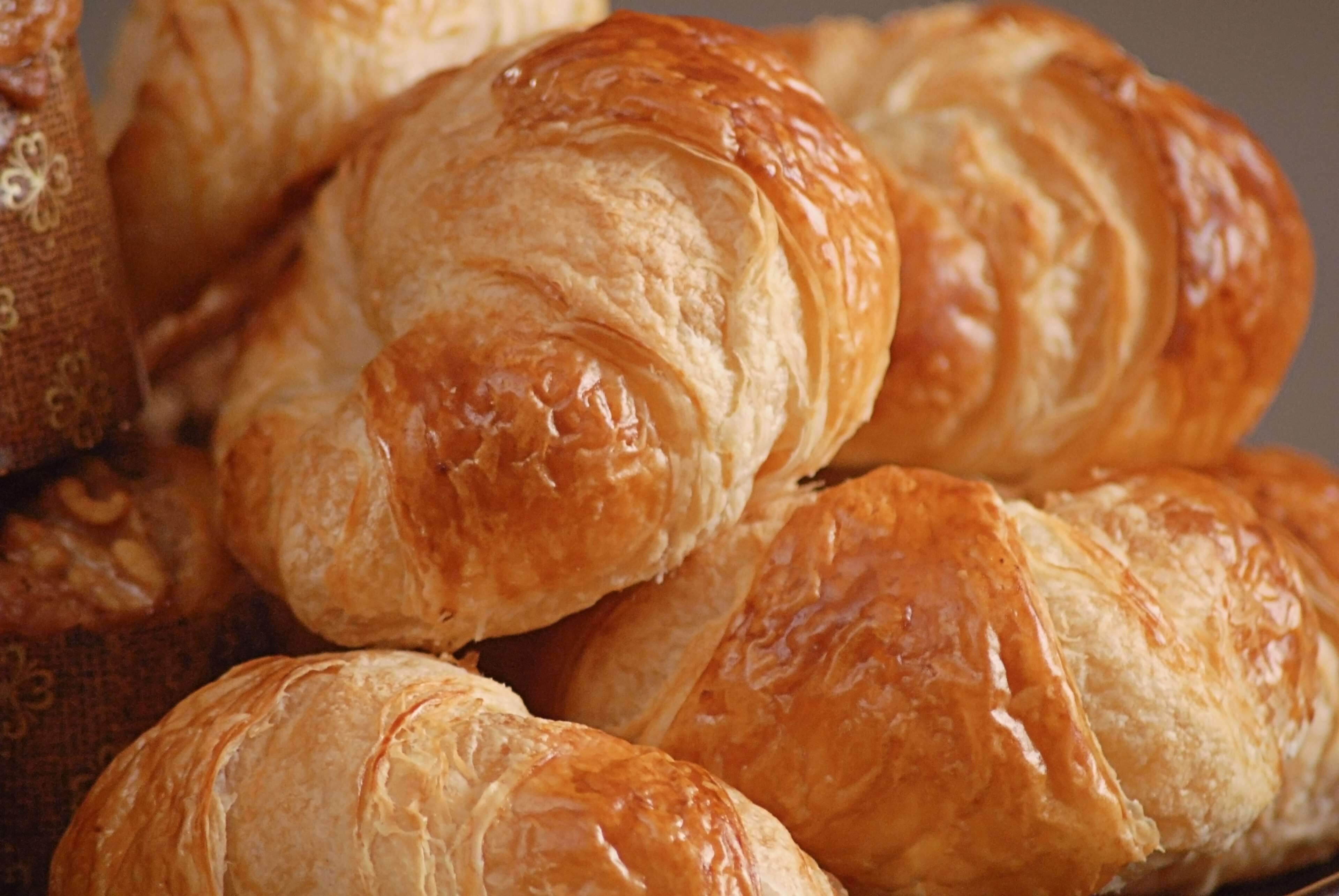A close-up of golden-brown pastries, likely croissants, with a glossy finish.