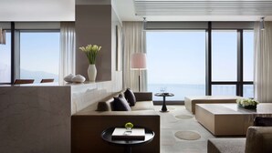 A modern hotel room with a large window offering a view of the city and a pier. There is a seating area with a sofa and a small table with a vase of flowers. - Grand Hyatt Dalian (Dalian)