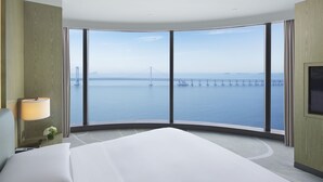 Una habitación de hotel moderna con una cama grande, televisión, lámpara y vistas a un puente sobre el agua.