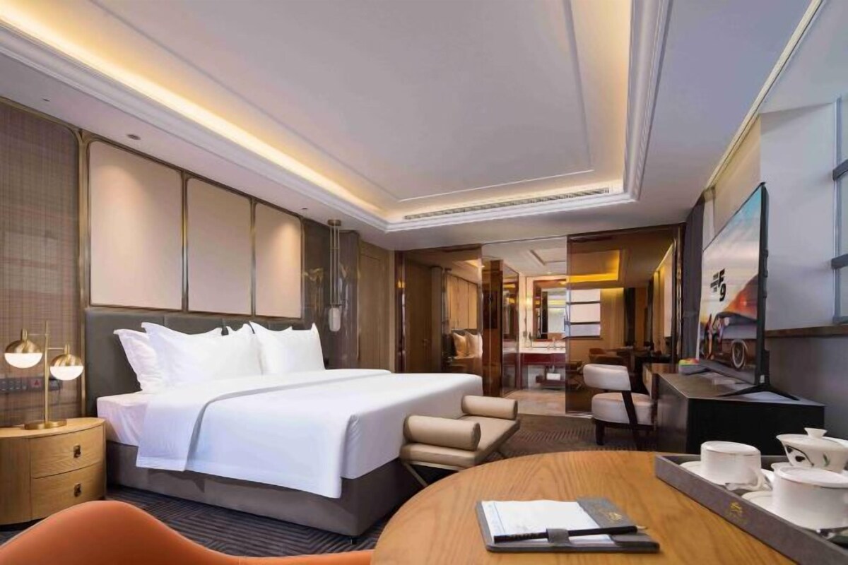 Una habitación de hotel moderna con una cama grande, mesitas de noche, un escritorio y una zona de estar.