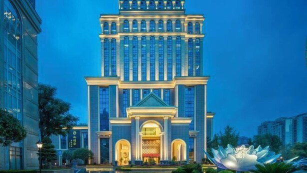 A large, modern building with a symmetrical facade, multiple windows, and a central entrance with a decorative archway. - Nanxi Juyang Hotel (Yibin)