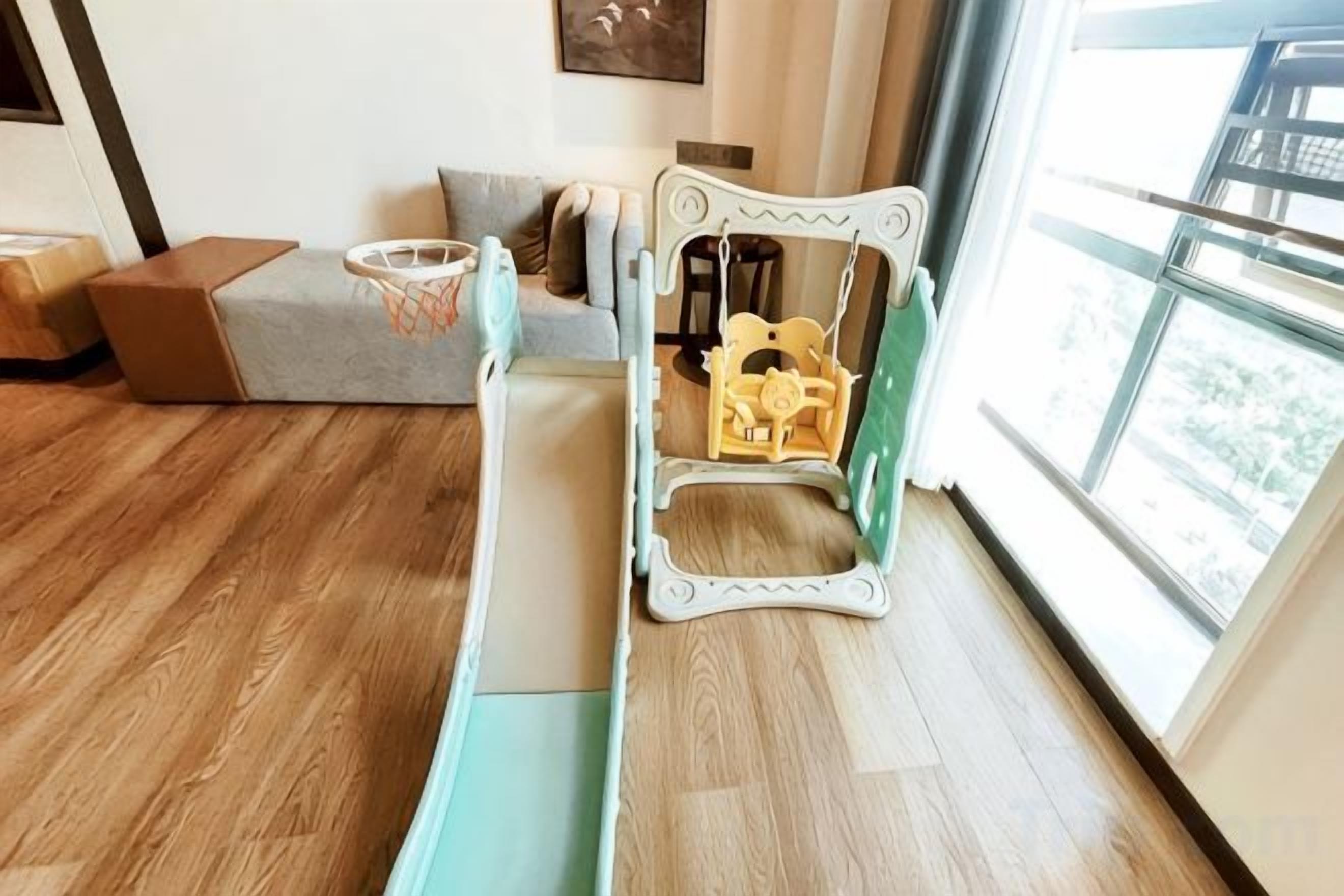Una habitación con piso de madera, un sofá, una mesita y una ventana con vistas.