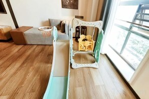 A room with a wooden floor, a sofa, a small table, and a window with a view.