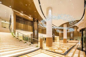 A spacious lobby with a grand staircase, large pillars, and a decorative light installation. - Nanxi Juyang Hotel (Yibin)