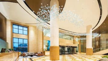 Eine geräumige Lobby mit hoher Decke, großen Säulen und einem gemusterten Boden.