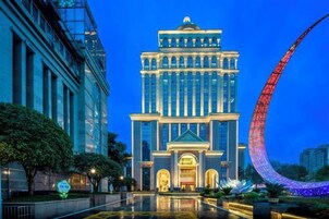 A modern hotel with a prominent tower, large windows, and a reflective courtyard.