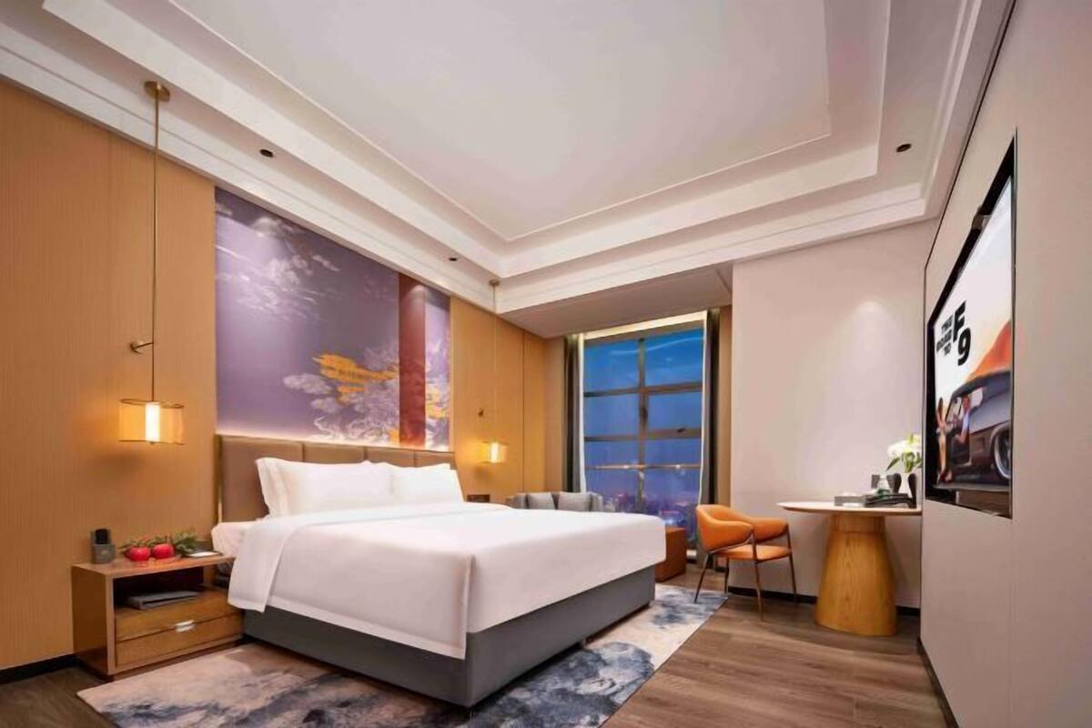 Ein modernes Hotelzimmer mit einem großen Bett, einem Schreibtisch und einem Stuhl.