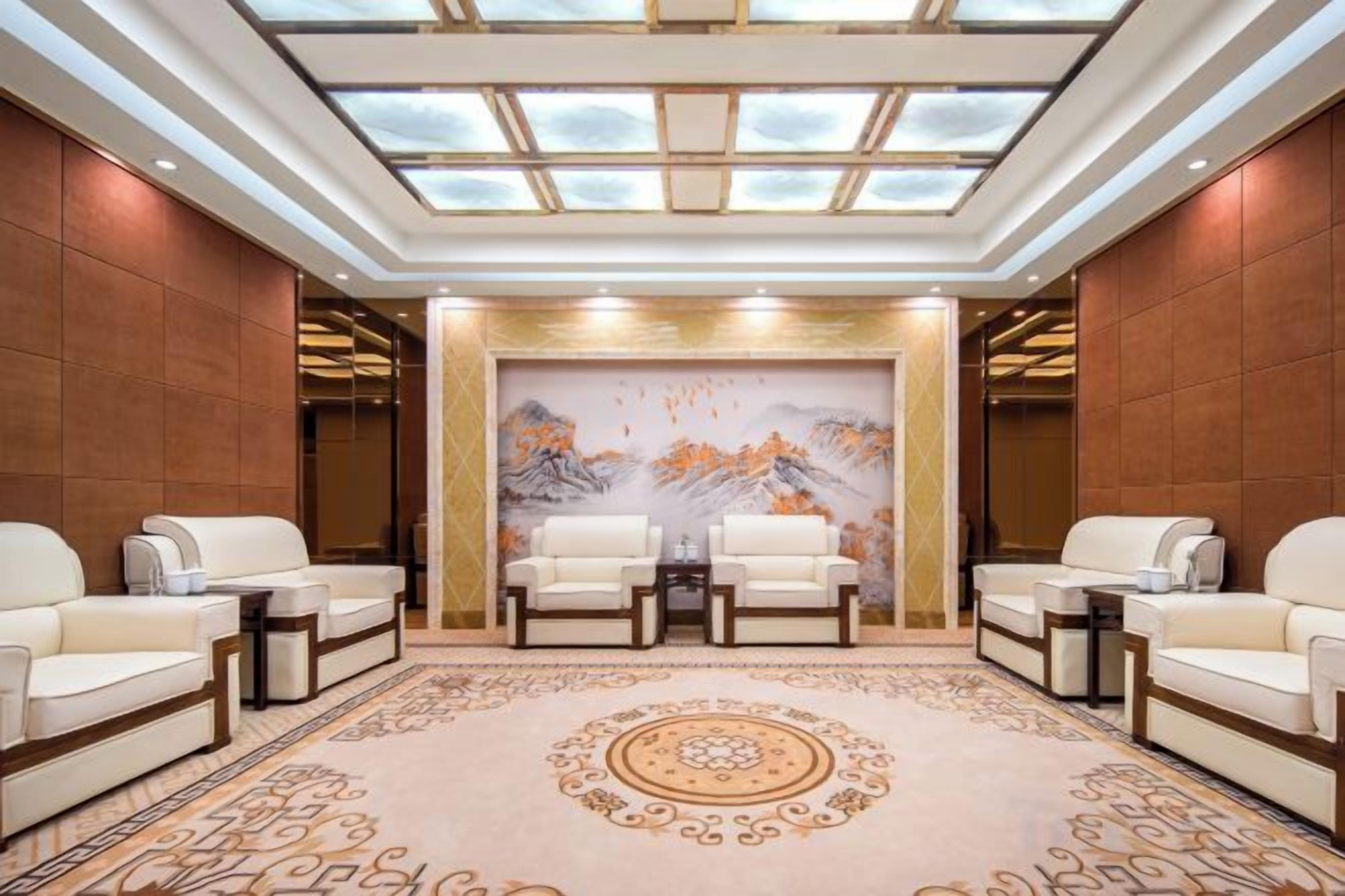 Eine geräumige Lobby mit hoher Decke, einem großen Wandgemälde und vier Sitzbereichen.