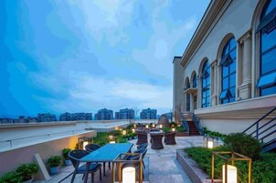 Una terraza en la azotea con mobiliario exterior, una escalera y vistas de la ciudad.