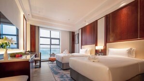 A hotel room with two beds, a desk, a chair, a window with a view, and a large mirror. - Nanxi Juyang Hotel (Yibin)