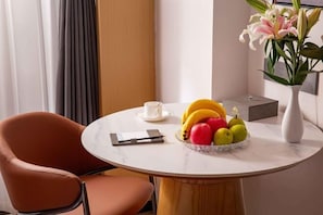 Una mesa redonda de mármol con un frutero, una taza blanca y un jarrón con flores.