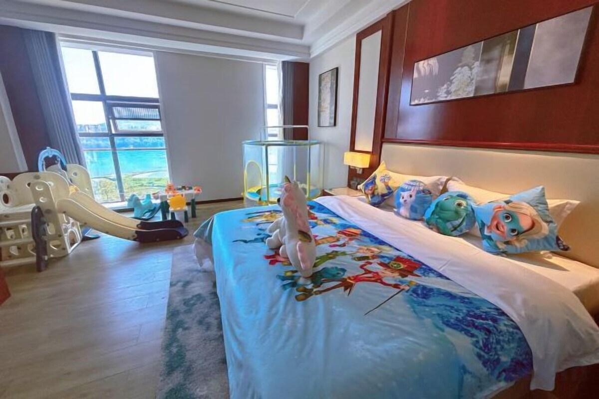 A hotel room with a bed, a glass fish tank, and a view of the outdoors.