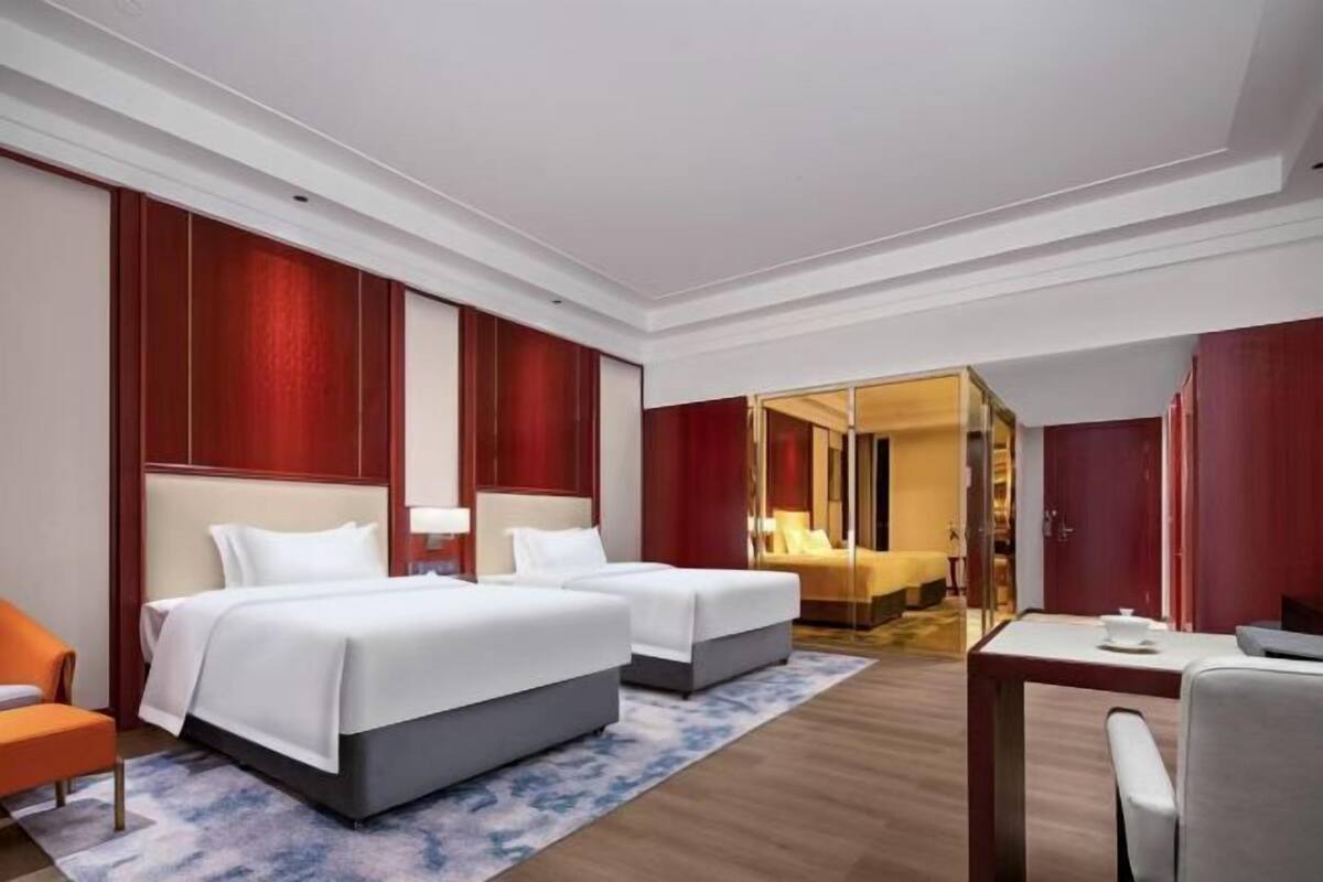 Ein Hotelzimmer mit zwei Betten, einem Schreibtisch, einem Stuhl und einem Spiegel.