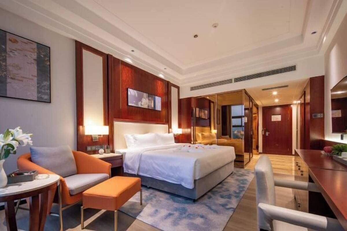 Ein Hotelzimmer mit Bett, Schreibtisch, Stuhl, kleinem Tisch und Nachttisch.