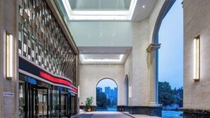 A hotel lobby with a glass facade, a central archway, and a view of the cityscape. - Nanxi Juyang Hotel (Yibin)