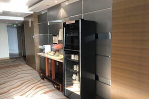 A hotel reception area with a modern design, including a reception desk, a refrigerator, and a wall-mounted information board. - Huatian Hotel (Shaoyang)