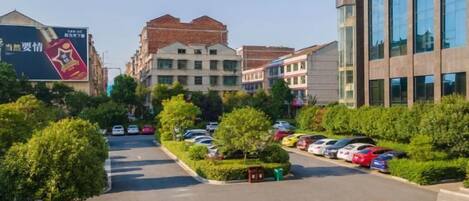 A street view with parked cars, trees, and buildings.