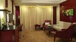 A hotel room with a desk, two armchairs, a sofa, a coffee table, and a large window with curtains. - Yuji Royal Grand Hotel (Xiaogan)