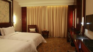 A hotel room with a bed, a desk, a chair, a television, and a curtain. - Yuji Royal Grand Hotel (Xiaogan)