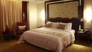 A hotel room with a large bed, a chair, a desk, and a map on the wall. - Yuji Royal Grand Hotel (Xiaogan)