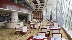 A spacious restaurant with high ceilings, large windows, and a central bar area. - Yuji Royal Grand Hotel (Xiaogan)