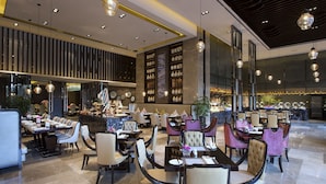 A modern restaurant with multiple dining areas, including a bar and a seating area with tables and chairs. - Wanda Vista Kunming (Kunming)
