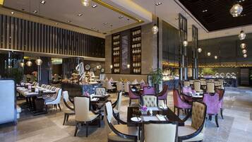 A modern restaurant with multiple dining areas, including a bar and a seating area with tables and chairs.