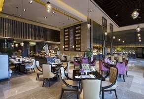 Un ristorante moderno con diverse aree ristorazione, tra cui un bar e un'area con tavoli e sedie.