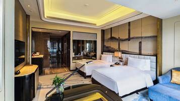 A hotel room with a large bed, a desk, a TV, and a sofa.