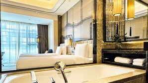 A modern hotel room with a large bed, a bathroom with a marble sink, and a view of the city. - Wanda Vista Kunming (Kunming)