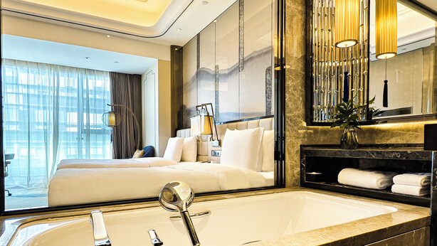 A modern hotel room with a large bed, a bathroom with a marble sink, and a view of the city. - Wanda Vista Kunming (Kunming)
