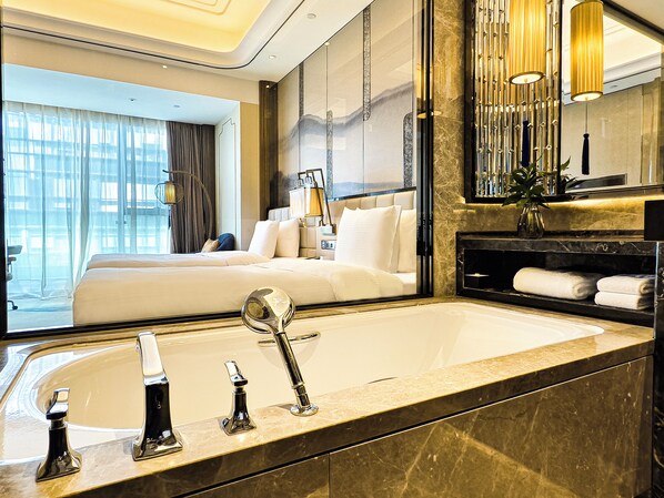 A modern hotel room with a large bed, a bathroom with a marble sink, and a view of the city. - Wanda Vista Kunming (Kunming)
