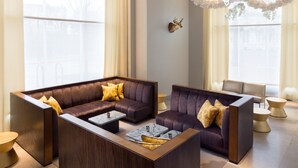 Un moderno vestíbulo con un sofá modular, una mesa de centro y un elemento decorativo en el techo.
