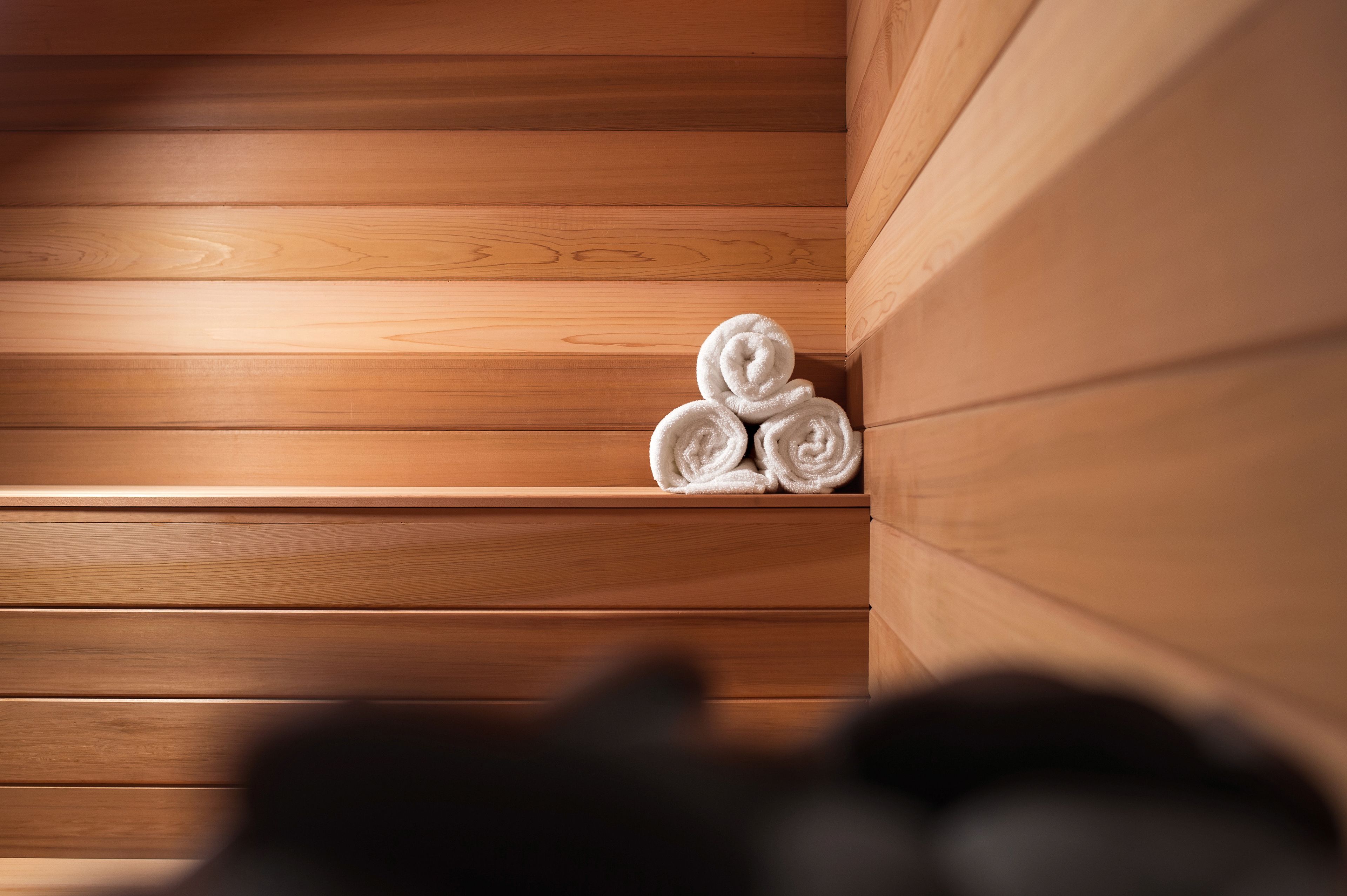 Una sauna de madera con tres toallas enrolladas en un estante.