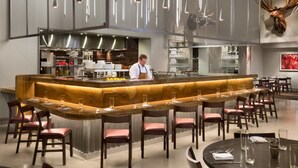 Un restaurante moderno con barra central, techo alto e iluminación contemporánea.