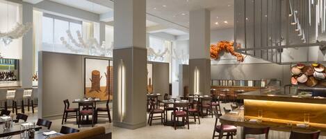 A spacious restaurant with high ceilings, modern lighting, and a variety of seating arrangements including booths and tables.