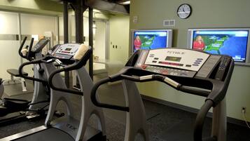 A gym with treadmills, a wall clock, and weather forecast screens.