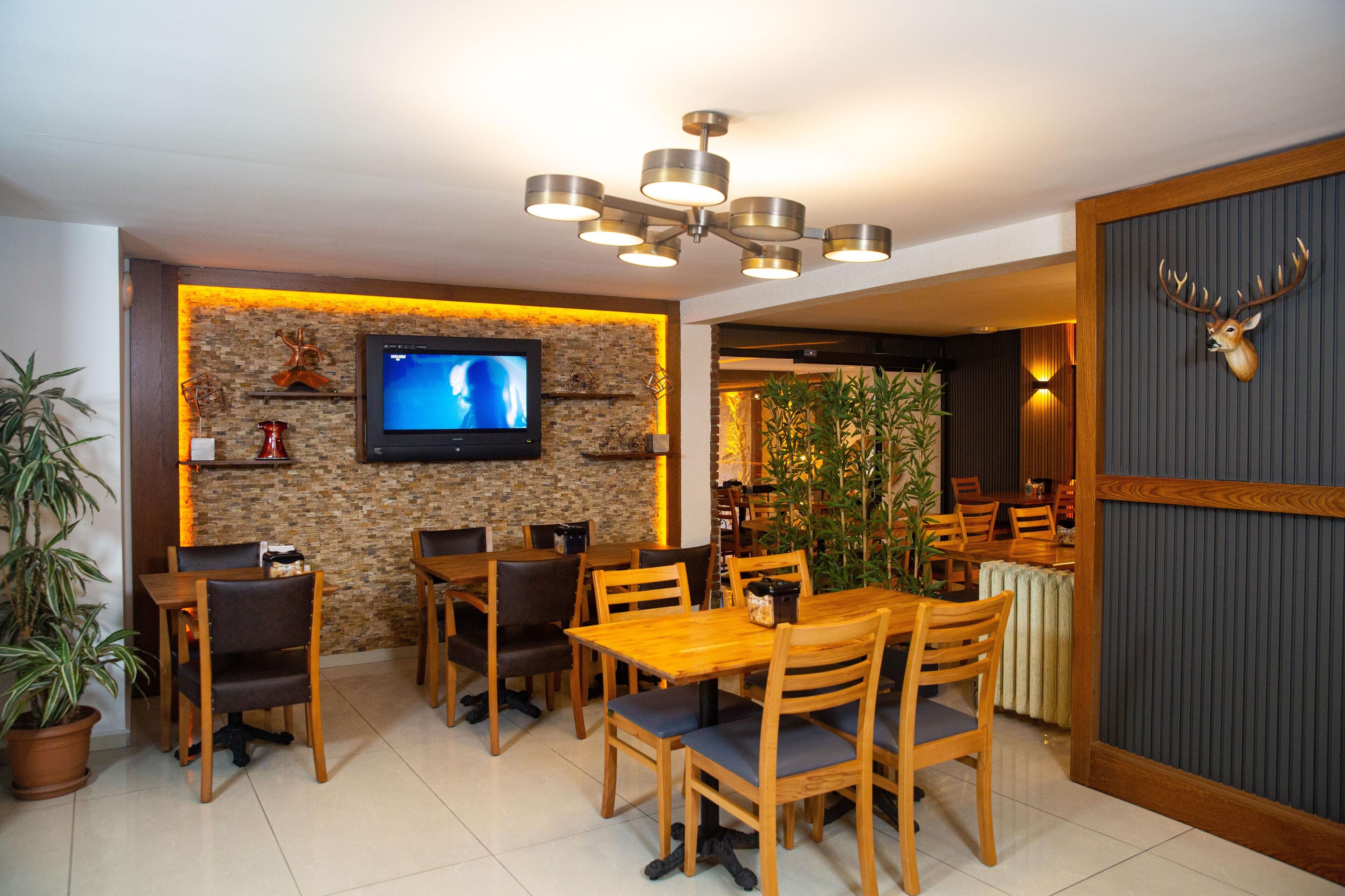 A dining area with wooden tables and chairs, a mounted TV, and decorative wall elements.