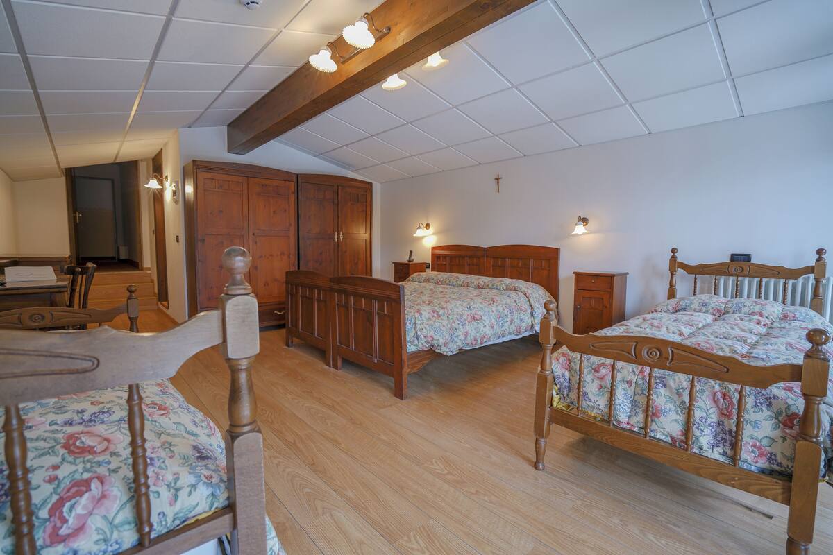 Ein Schlafzimmer mit zwei hölzernen Betten, einem Holzschrank und einem Schreibtisch mit Stuhl.