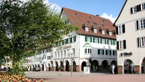 Ein Hotel im traditionellen europäischen Baustil, mit auffälligem Schild, Bogenfenstern und einem Ziegeldach.