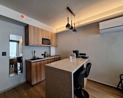 Una cucina moderna con mobili in legno, un forno a microonde integrato, un piano di lavoro in granito e un angolo bar con due sedie nere.