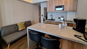 A compact kitchen with a central island, a built-in microwave, and a coffee maker. - Hotel Block Suites (Mexico City)