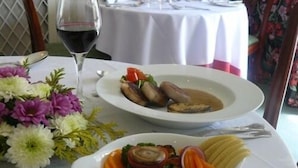 A dining table with a white tablecloth, a glass of red wine, and two plates of food. - Simonsbath House (Minehead)