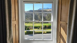 A bay window with six panes, offering a view of a green landscape with trees and hills. - Simonsbath House (Minehead)