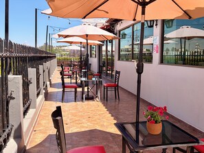 An outdoor seating area with tables and chairs, umbrellas, and a view of the cityscape. - Sleep Inn Puebla Centro Histórico (Puebla)